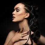 Captivating studio portrait featuring a woman with braided hair adorned with barbed wire, set against a dark background.
